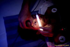 Auscultation of an injured person with a white Snaplight light stick in emergency medicine